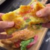 A golden-brown, crispy Turkish potato breakfast wrap (Crunch Bomb) served on a plate, featuring a shredded potato crust, melted cheese, and fresh arugula.