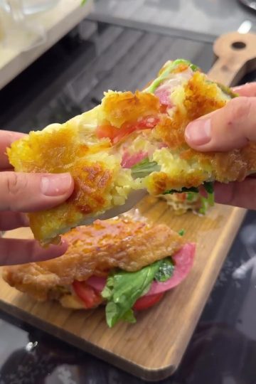 A golden-brown, crispy Turkish potato breakfast wrap (Crunch Bomb) served on a plate, featuring a shredded potato crust, melted cheese, and fresh arugula.