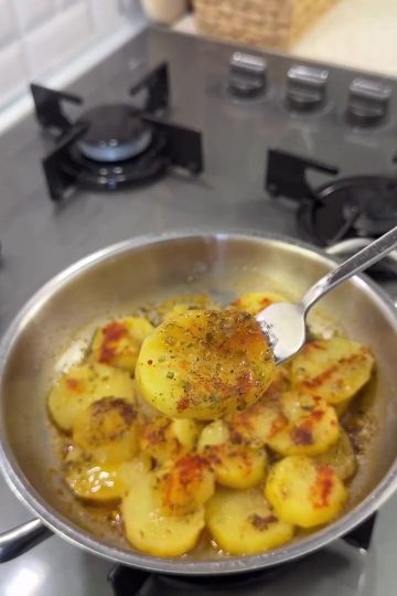 Sliced breakfast potatoes cooked in a pan with butter, thyme, and paprika, served hot.
