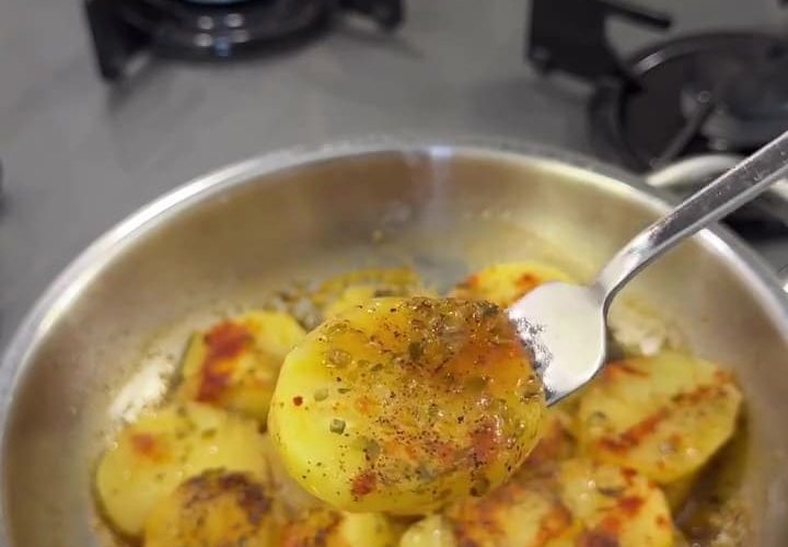 Sliced breakfast potatoes cooked in a pan with butter, thyme, and paprika, served hot.