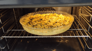 Freshly baked Turkish style leek cake topped with nigella seeds in a glass baking dish.