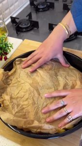 Arranging baby potatoes and onions around the fish and coating them with the remaining sauce.