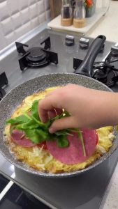 Pouring whisked eggs over a layer of crispy fried potatoes in a non-stick pan