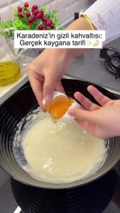 Cracking four eggs into the flour and milk mixture, ready to be whisked in.