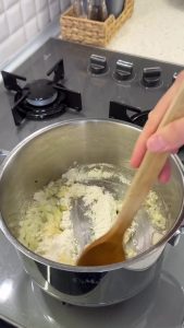 Adding all-purpose flour to the sautéed onions to create a thickening roux for the zucchini soup.