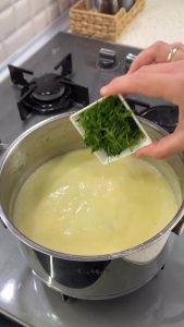 Stirring a handful of finely chopped fresh dill and salt into the creamy zucchini soup.