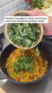 Adding a bowl of chopped fresh purslane (semizotu) to the sautéed vegetable base.