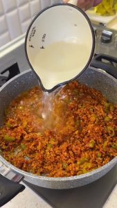 Gently adding the pre-fried golden eggplant cubes to the seasoned bulgur mixture.
