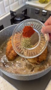 Adding minced garlic, thyme, and paprika to the pan with the seared chicken for flavor.