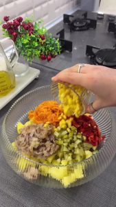 Adding cornichon pickles, sweet corn, and fresh dill to the potato and vegetable mix.