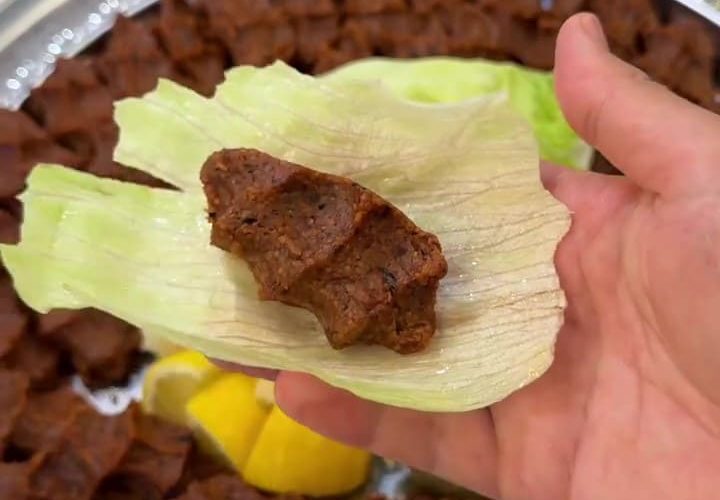 A platter of hand-shaped Turkish meatless çiğ köfte with lettuce and lemon wedges.
