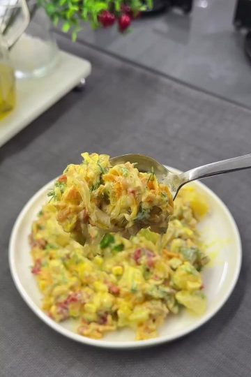 A vibrant and creamy Turkish potato salad served in a bowl, featuring a golden curry-yogurt dressing, diced roasted red peppers, sweet corn, and garnished with fresh dill.