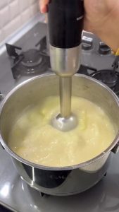 Using a hand immersion blender to process the cooked zucchini into a smooth, velvety texture.