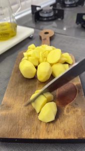 Boiling peeled and small-diced potatoes in a pot for the salad base.