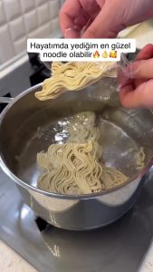 Boiling three packs of noodles in a pot of water on the stove.