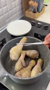 Searing chicken drumsticks in a pot until the skin is golden and flavorful.