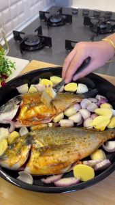 Applying the garlic-lemon marinade over the sea bream using a kitchen brush.