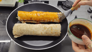 Brushing the outer surface of the rolled fish wrap with a spicy red oil glaze for extra crunch.