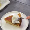 A slice of caramelized peach upside-down cake served with vanilla ice cream on a plate.