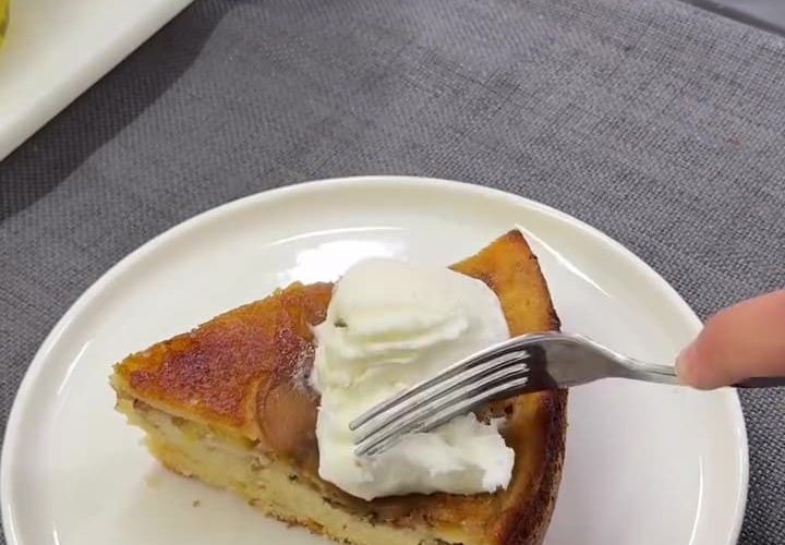 A slice of caramelized peach upside-down cake served with vanilla ice cream on a plate.