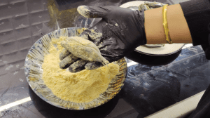 Coating the stuffed anchovies thoroughly in yellow cornmeal to ensure a crispy texture after frying.