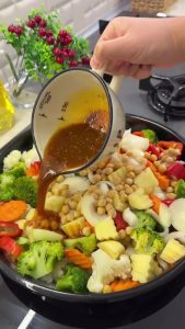 Tossing the winter vegetables and chickpeas in the golden spiced oil for even coating before baking.