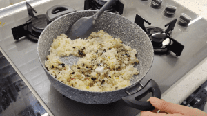 The aromatic rice filling cooking in a pot, showing currants, pine nuts, and spices mixed in.