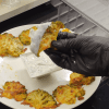 A tray of golden-brown smashed broccoli topped with melted kashar cheese, served with a side of garlic yogurt dip.
