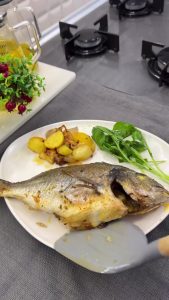 The final result of perfectly roasted, golden-brown and crispy sea bream with baby potatoes.