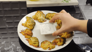 Finished crispy baked cheesy broccoli served hot with a side bowl of garlic and dill yogurt dip.