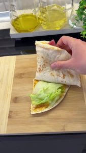 Adding labneh, tomatoes, salami, and greens to the four quadrants of the egg-tortilla.