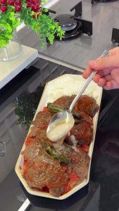 Pouring hot melted butter over the finished İskender Kebap for the final touch.