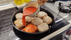Flipping the bowl to release a round cabbage bundle onto a baking tray.