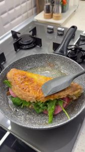 Layering kashar cheese, beef salami, tomato slices, and fresh arugula on the potato omelet