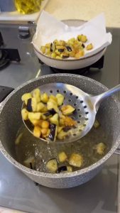 Frying small eggplant cubes in a pan until golden and crispy for the pilaf.
