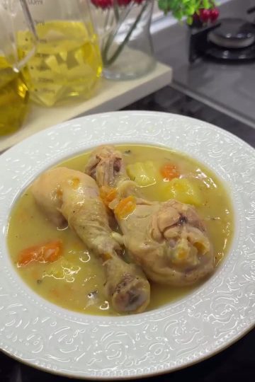 A hearty bowl of Turkish chicken stew (Tavuk Haşlama) with tender drumsticks, carrots, and potatoes in a golden broth.