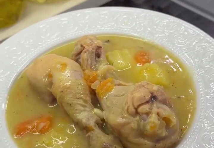 A hearty bowl of Turkish chicken stew (Tavuk Haşlama) with tender drumsticks, carrots, and potatoes in a golden broth.