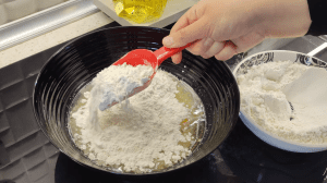 Adding flour to the bowl and kneading a soft, slightly sticky dough by hand.