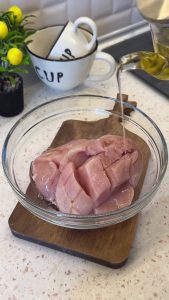 Marinating chicken fillets with vinegar and vegetable oil in a glass bowl to make them tender.