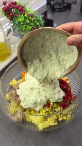 Pouring the yellow curry yogurt dressing over the salad ingredients and mixing well.