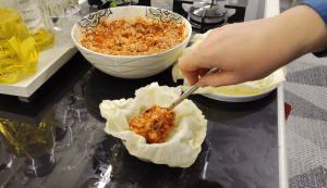 Mixing rice, ground beef, and spices in a glass bowl for the filling.