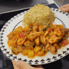 A colorful baking tray filled with roasted chicken cubes, eggplants, potatoes, and peppers in a rich tomato sauce.