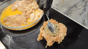 A thinned, marinated chicken thigh lining the inside of a small deep bowl, ready for filling.