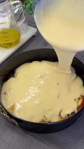 Pouring the finished cake batter into the pan over the caramelized peach and walnut layer.