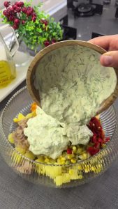 Pouring the golden creamy curry and yogurt sauce over the mixed vegetable ingredients.