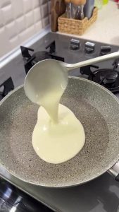 Pouring the 3-ingredient liquid dough into a hot pan with a ladle to form a thin flatbread.