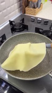 Pouring the 3-ingredient liquid dough into a hot pan with a ladle to form a thin flatbread.