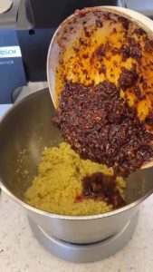 Combining the prepared aromatic spicy sauce with the softened and rested bulgur wheat.