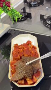 Pouring warm tomato sauce over toasted bread cubes for the base of the İskender.