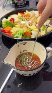 Whisking olive oil with turmeric, curry powder, thyme, and red pepper flakes in a small bowl.